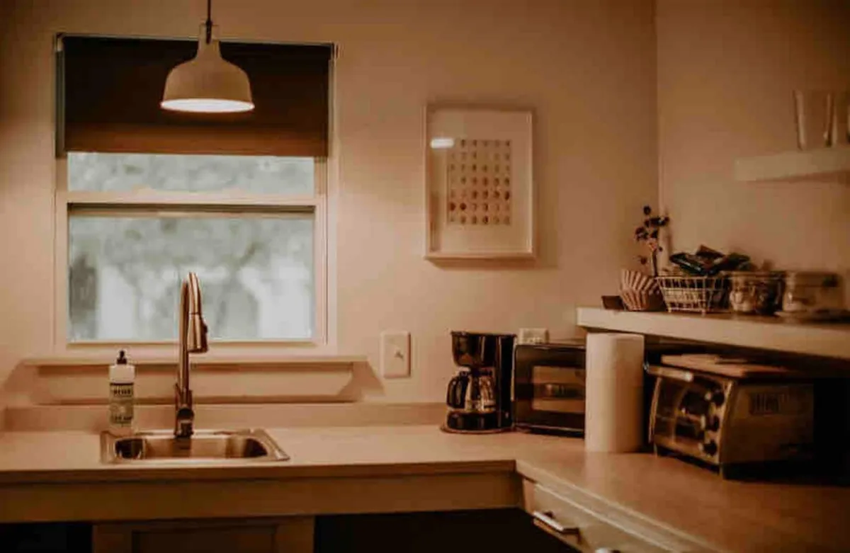 A bright kitchenette scene with a sink, coffee maker, and a sunny window. This space is ideal for preparing casual meals or snacks, brewing coffee in the morning, and gathering for shared moments after a day outside.