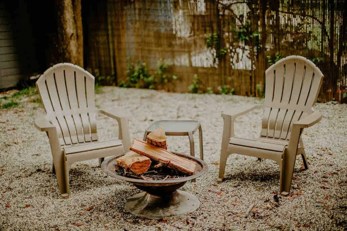 A classic fire pit area with several Adirondack chairs arranged on a gravel base, perfect for sharing stories or unwinding in the fresh air.